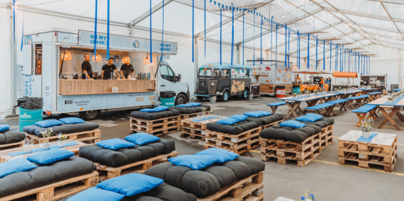 Mitarbeiteranlass zum 100 Jahre Jubiläum Festlich dekoriertes Zelt mit Tischen, Stehtischen, Sofas in der Firmenfarbe blau.