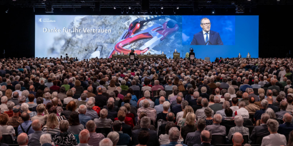 Generalversammlung der LUKB grosse Leinwand mit Rednerpult und Gästen an der GV der LUKB