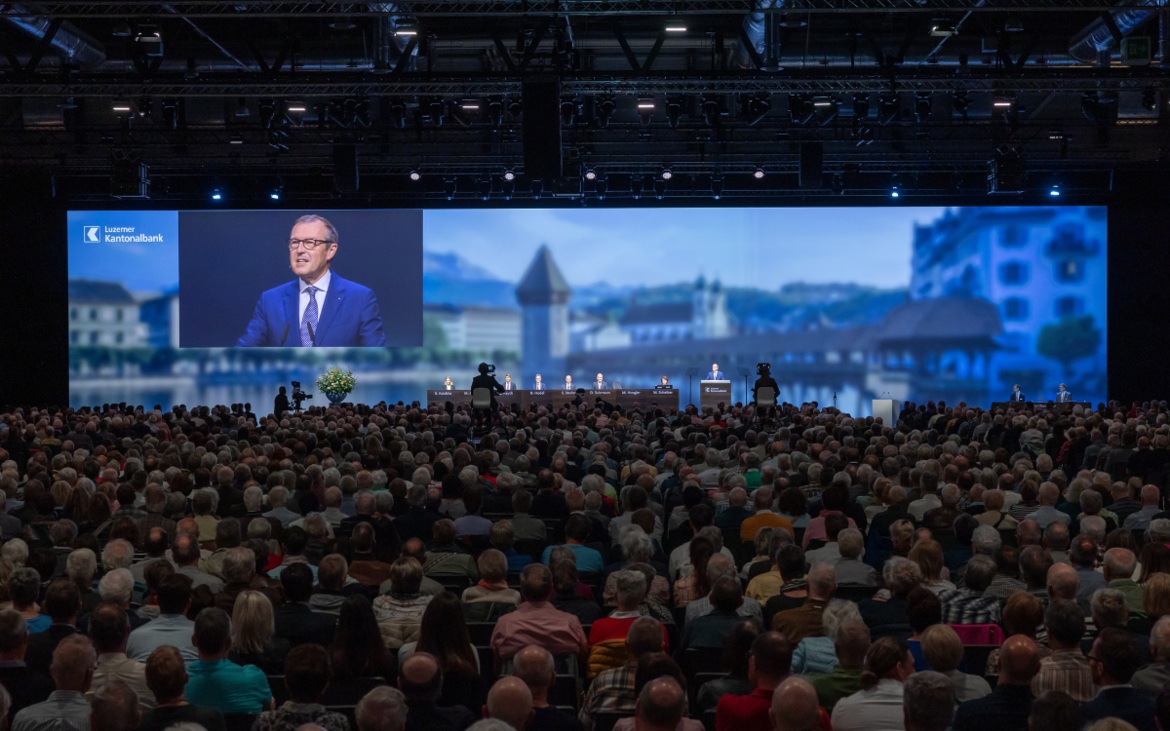 Grosse Leinwand mit Podium und Gästen an der GV der LUKB